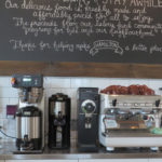 man standing in front of coffee machines while on his phone