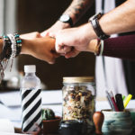 5 people giving a fist bump as a team